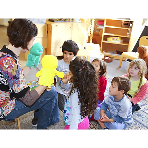 Children with teacher using puppets in small group setting
