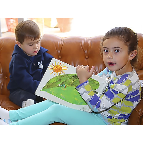 Two children on couch reading book