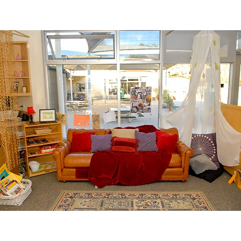 Large group and reading area with sofa and quiet reading nook with pillows and natural light